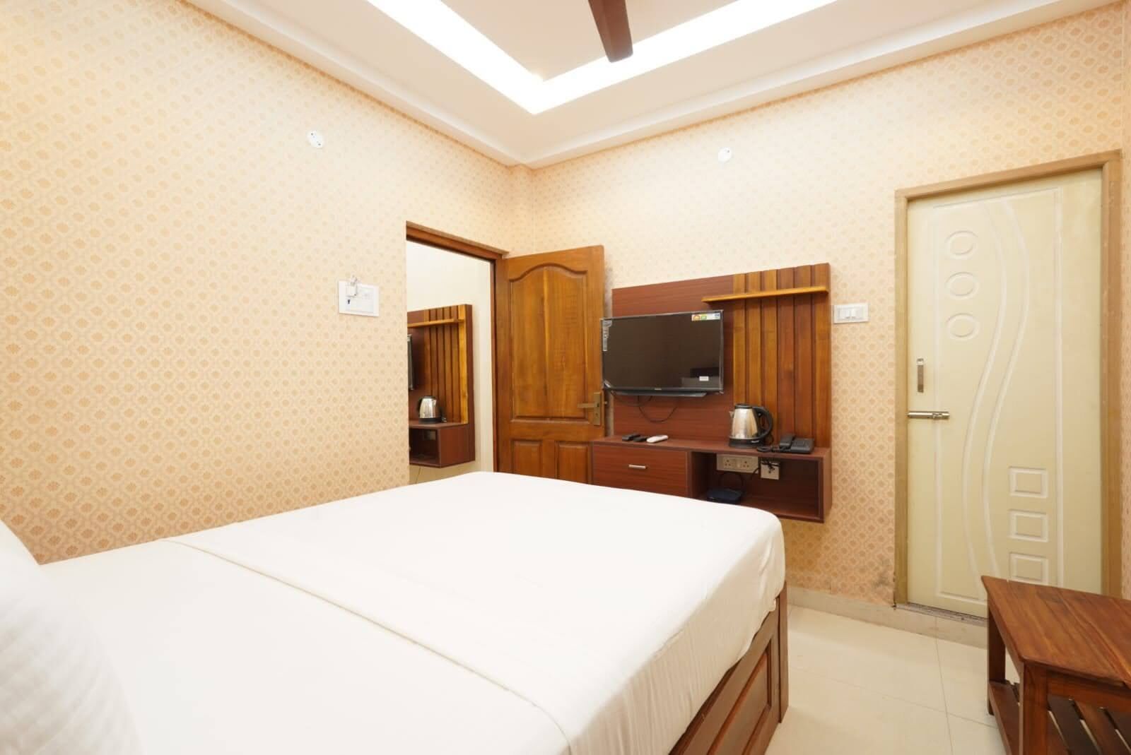 A hotel room with a bed, a TV, a wooden cabinet, and a door with a unique design.