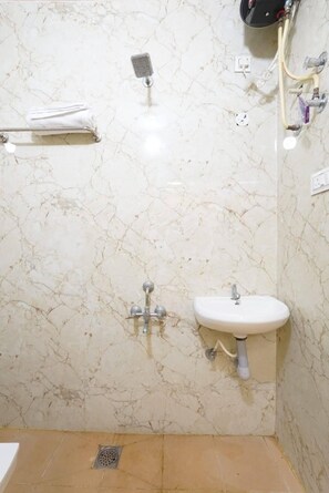 A bathroom with a marble wall, a sink, a shower, and a towel rack.
