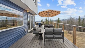 Eine Terrasse mit Gartenmöbeln, darunter eine Couch und Stühle, sowie ein großer Sonnenschirm.