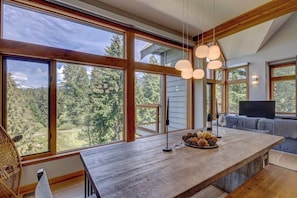 A spacious kitchen with large windows, a wooden island, and a cozy seating area with a TV.