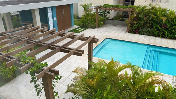A pool area with a pergola and lush greenery. - Vive Luxe Condo , Pool & 24/7 Security near Airport (D'Abadie)