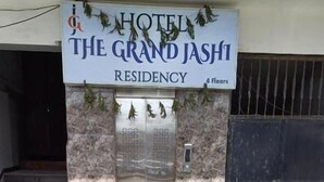 The entrance to The Grand Jashi Residency Hotel, featuring a stone facade, a green artificial lawn, and a double door with a glass panel. - Hotel The Grand Jashi Residency (Patan)