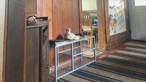 A room with wooden paneling, a mirror, a framed picture, a poster, a small table with a kettle, and a chair.