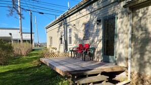 Una casa con terraza de madera, mobiliario exterior y jardín.