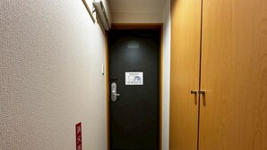 A narrow hallway with a carpeted floor, a door with a fire alarm sign, and a wooden door on the right. - GRACE GARDEN 301 (Sapporo)