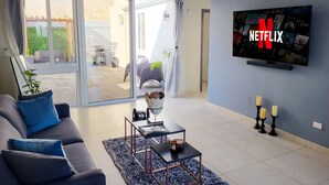 Een moderne woonkamer met een bank, salontafel en een televisie waarop het Netflix logo wordt weergegeven.