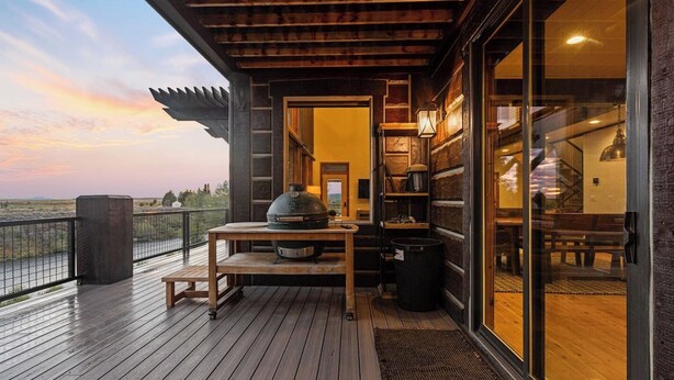 Een houten terras met een barbecue en een tafel, met uitzicht op een prachtig landschap.