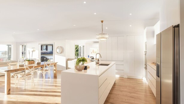 A modern kitchen with white cabinetry, a central island, and a stainless steel refrigerator. - Springcombe Sunset - St Heliers Beach House (Auckland)