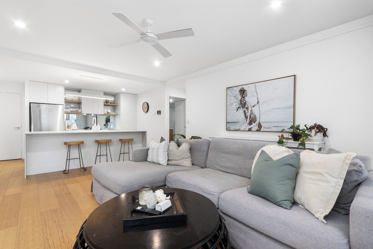 Un salon moderne avec un canapé gris, une table basse et un ventilateur de plafond.