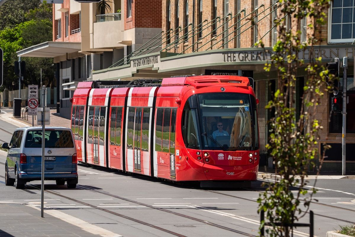 A red tram on a city street with a building labeled 'The Great Southern House' in the background.