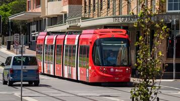 A red tram on a city street with a building labeled 'The Great Southern House' in the background.