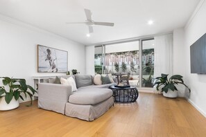 Un salon moderne avec un canapé d’angle, une table basse ronde et un ventilateur de plafond.