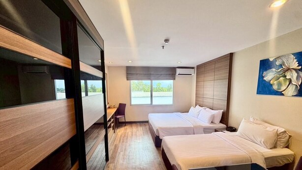 A hotel room with two beds, a desk, and a large window. - AMIS By Sima Thani (Nakhon Ratchasima)