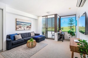 A modern living room with a dark sofa, a coffee table, and a dining area with a table and chairs.