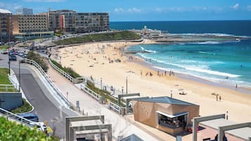 A coastal hotel with a beach view, a parking area, and a promenade.