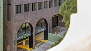 Un immeuble à plusieurs étages avec une façade en briques, une enseigne indiquant « ENTRÉE » et une autre indiquant « SORTIE SEULEMENT ».