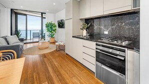 A modern kitchen with a black marble backsplash, stainless steel appliances, and a dining area with a wooden table and chairs.