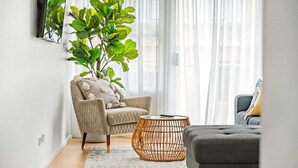 A living room with a sofa, armchair, and a large green plant. - Enjoyable East End (Newcastle)