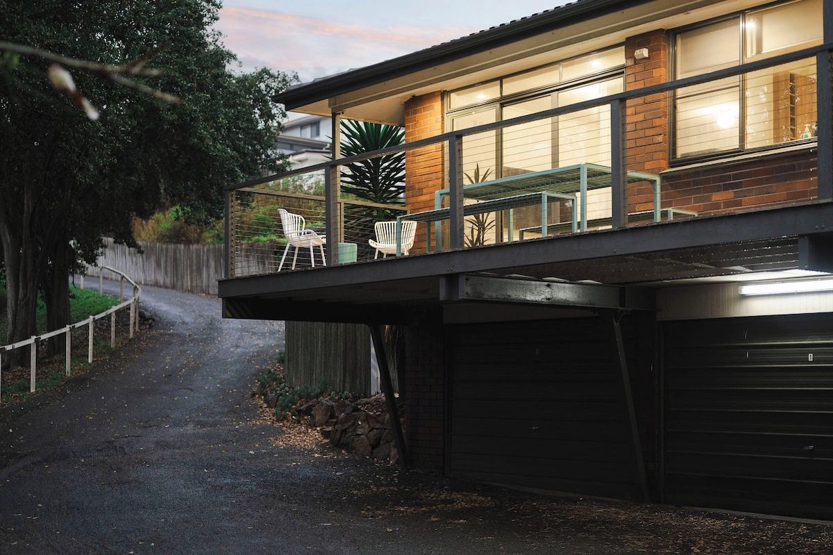 A modern house with a covered patio, a garage, and a pathway leading to the house.
