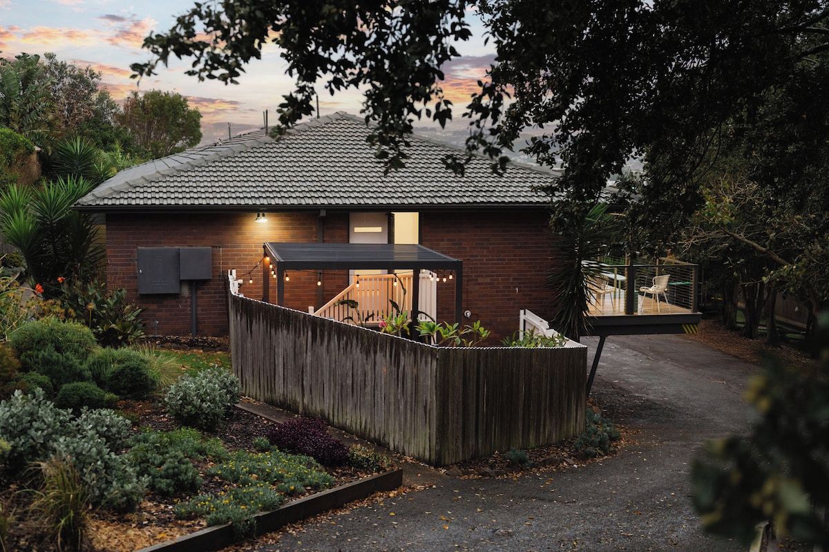 A house with a sloped roof, a fenced garden area, and a covered outdoor seating area.