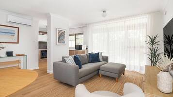 A modern living room with a grey sectional sofa, a striped armchair, and a wooden dining table.