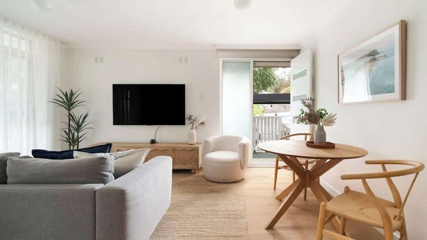 A modern living room with a sofa, a round dining table with chairs, a flat-screen TV, and a large window. - Bar Beach Bliss - 10 min walk to the Beach (Bar Beach)