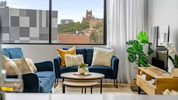A modern living room with a blue sofa, a round coffee table, and a view of a historic building through large windows.