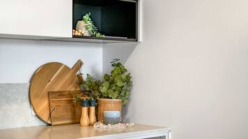 A kitchen counter with a wooden cutting board, a plant, and two spice containers.