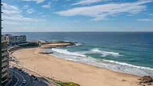 Una playa costera con una carretera curva y edificios al fondo.