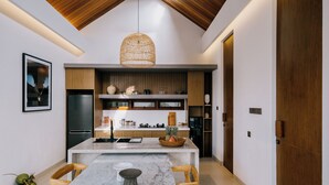 Una cocina moderna con una isla de mármol, sillas de madera y una lámpara colgante.