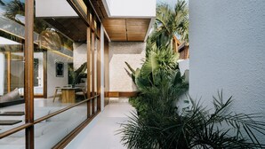 Un interior moderno con pared de vidrio, escalera de madera y plantas de interior.