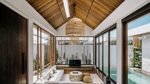 Una sala moderna con un gran techo de madera, un televisor y vistas a una piscina.
