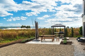 Eine Terrasse im Freien mit einem Pavillon, Picknicktischen und Grillplatz.