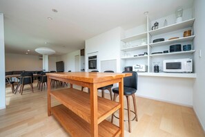 Eine moderne Küche mit weißen Schränken, einem Holztisch und einer eingebauten Mikrowelle.