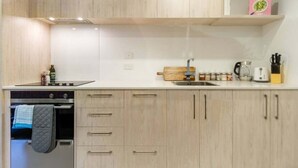A modern kitchen with light wood cabinets, a stainless steel range, and a built-in oven.