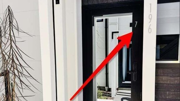 A modern building entrance with a white door, a black frame, and a red arrow pointing towards the door.