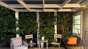 A patio area with wicker furniture, a small round table, and potted plants.