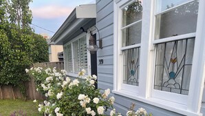 A residential house with a garden featuring white roses and a wooden fence.