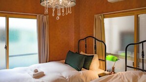 Hotellihuone, jossa on sänky, yöpöytä, lamppu ja kattokruunu.