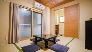 Perinteinen japanilainen huone, jossa on tatamimatto, liukuovi ja pieni pöytä tyynyineen.