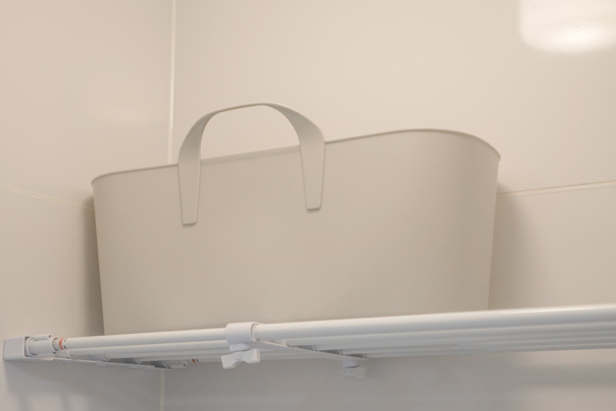 A white bathroom with a white towel rack and a white towel hanging on it.