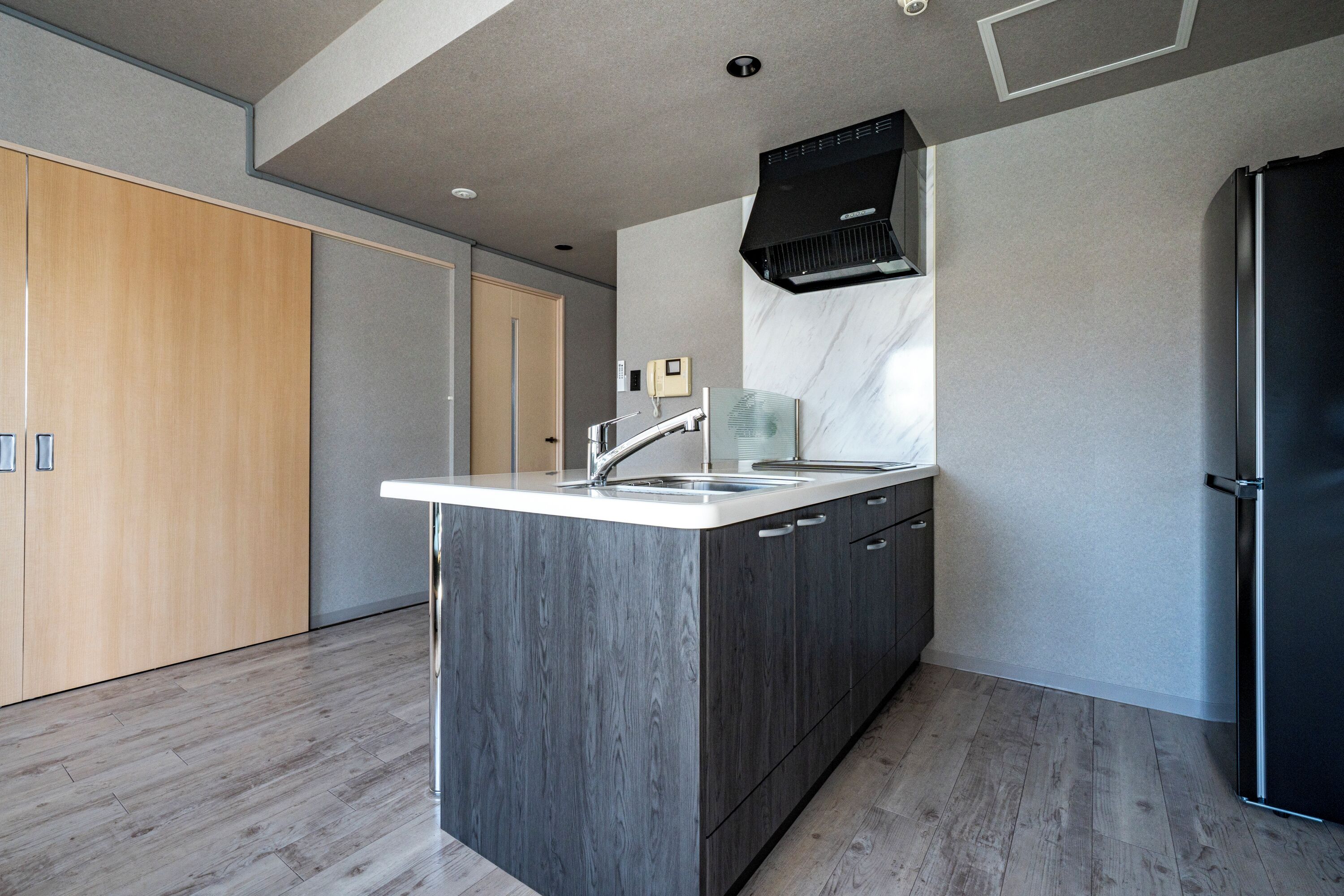 A modern kitchen with a central island, stainless steel appliances, and wooden cabinetry.