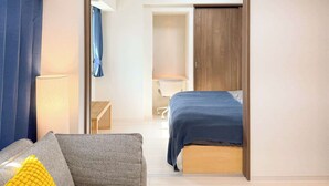 Ein modernes Hotelzimmer mit Bett, Sofa, Schreibtisch und Kleiderschrank.