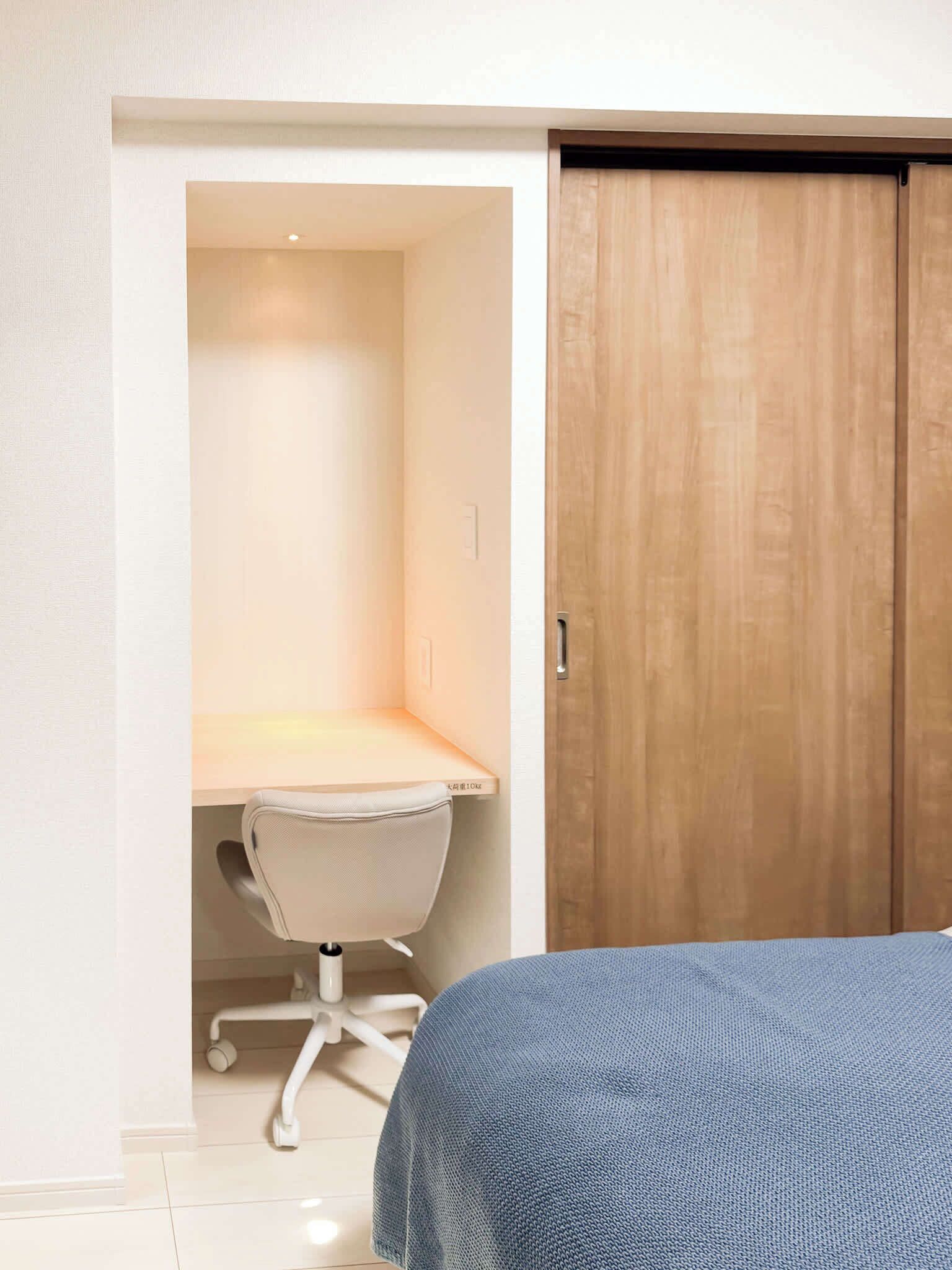 A bedroom with a bed, a desk, and a wardrobe.