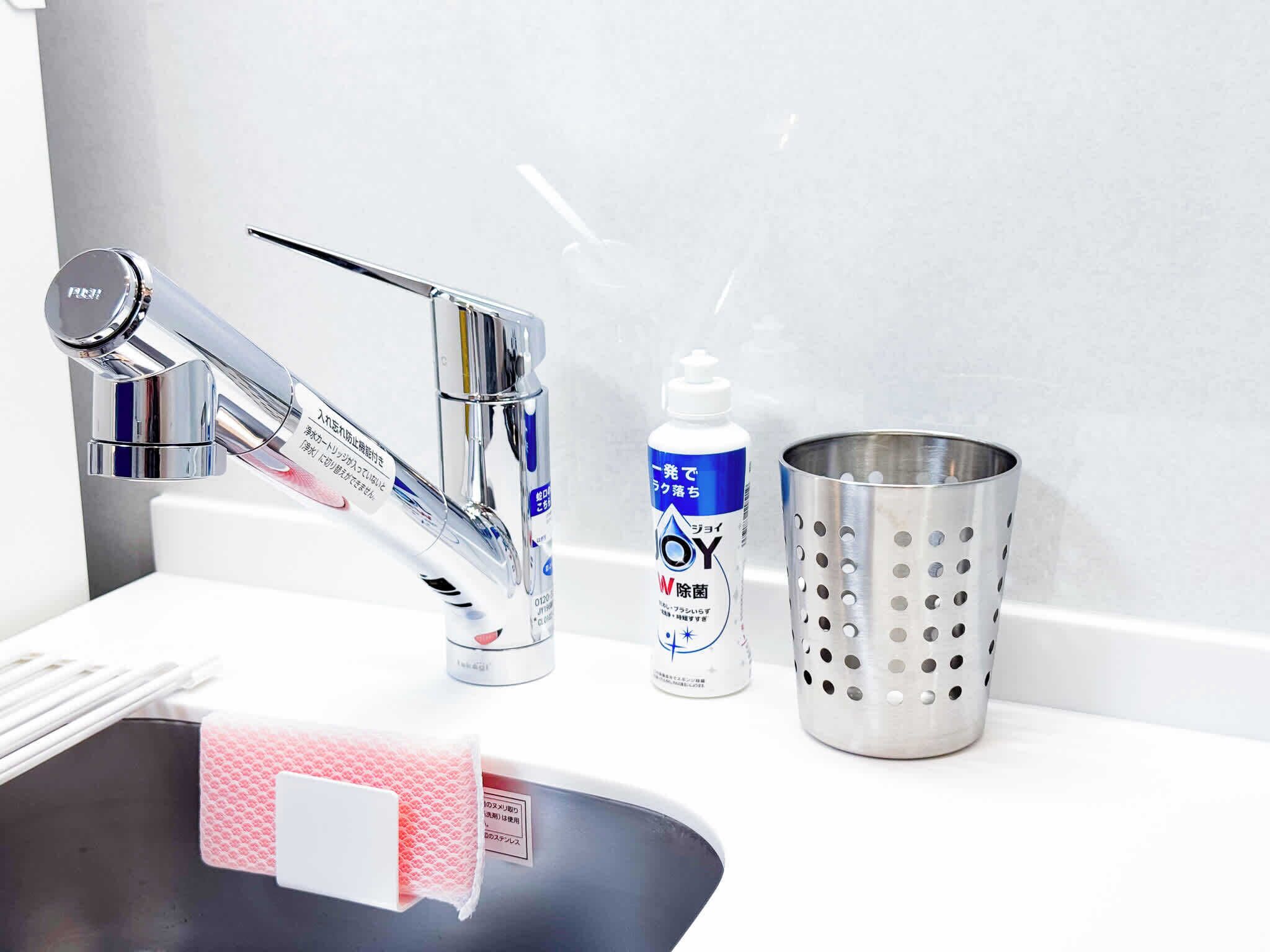 Un lavabo de bany amb un aixeta modern, una ampolla de sabó per mans i un colador metàl·lic.