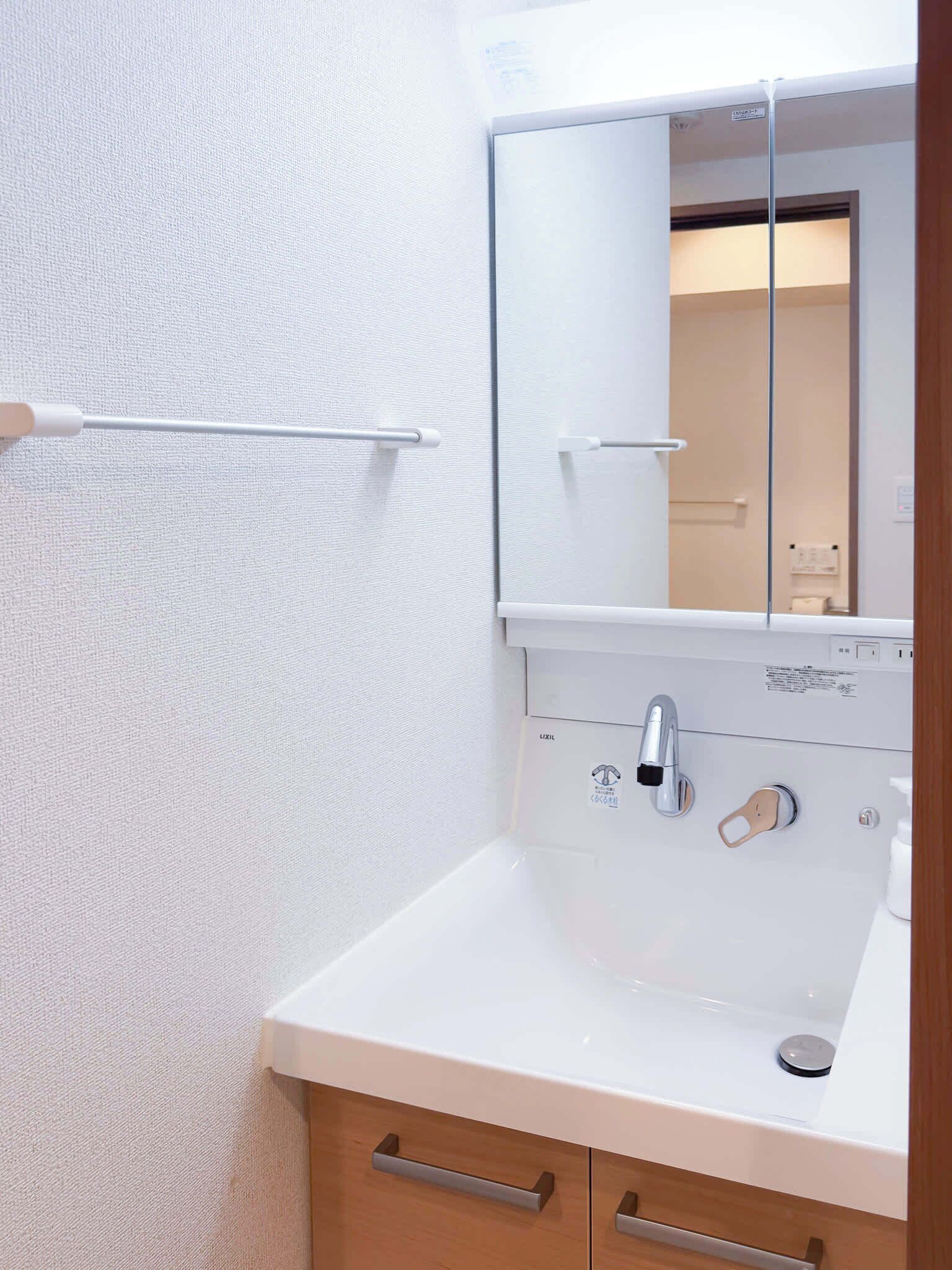 Un bagno con un lavandino bianco, uno specchio e un portasciugamani.