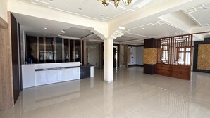 A spacious lobby with a reception desk, a decorative wooden partition, and a modern chandelier. - Hotel Raks  (Leh)