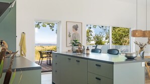 Een moderne keuken met een groot eiland, een eetgedeelte met uitzicht en een groot raam dat uitkijkt op een natuurlandschap.