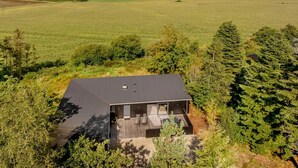 Een modern huis met een plat dak, omringd door weelderige begroeiing en uitzicht op zee.