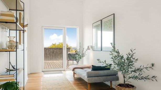 Een moderne woonkamer met een bank, een groot raam en uitzicht op de omgeving.